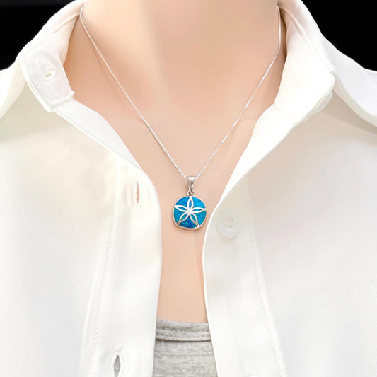 A close-up view of a person wearing a white shirt and a necklace with a blue pendant.
