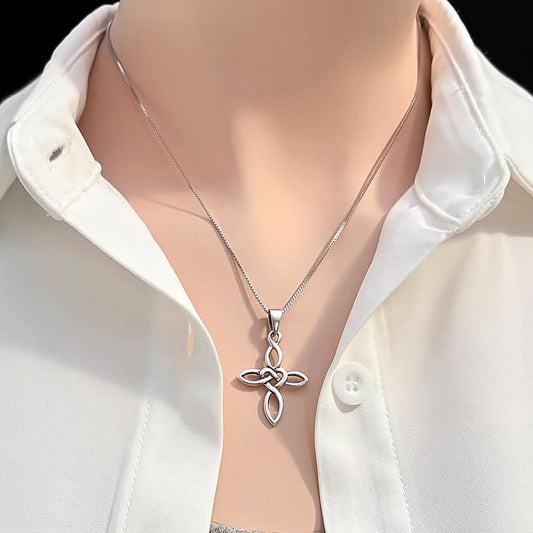 A silver cross pendant necklace is worn around a person's neck, with a white collared shirt visible underneath.