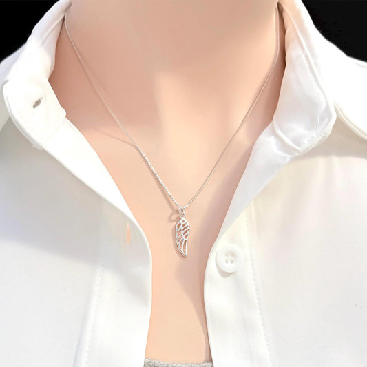 A silver necklace with a pendant is worn around a person's neck, who is wearing a white collared shirt.
