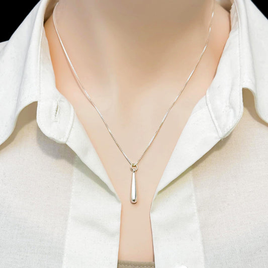 A close-up view of a person wearing a white collared shirt and a silver necklace with a pendant.