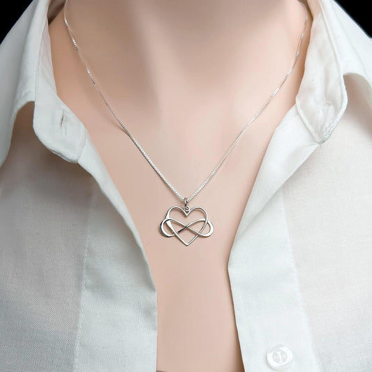 A silver necklace with a heart-shaped pendant is displayed on a mannequin wearing a white collared shirt.