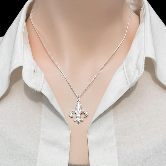 A silver necklace with a pendant is worn around a person's neck.