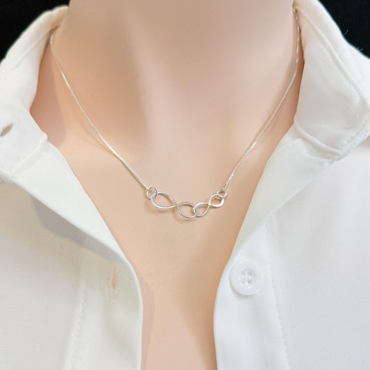 A close-up view of a silver necklace with a delicate design, worn around a person's neck.