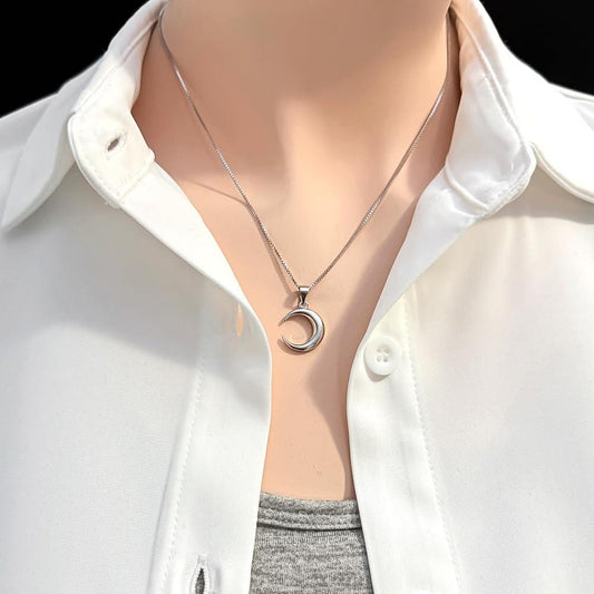 A close-up view of a person wearing a white collared shirt and a silver necklace with a pendant.