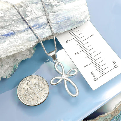 a silver cross pendant and a United States quarter coin placed on a blue surface.