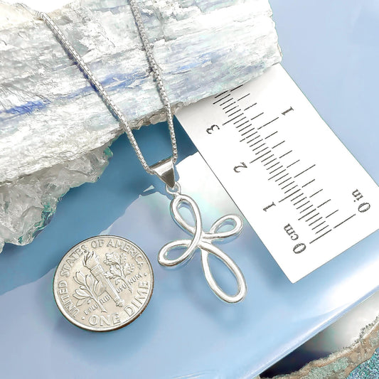 a silver cross pendant and a United States quarter coin placed on a blue surface.