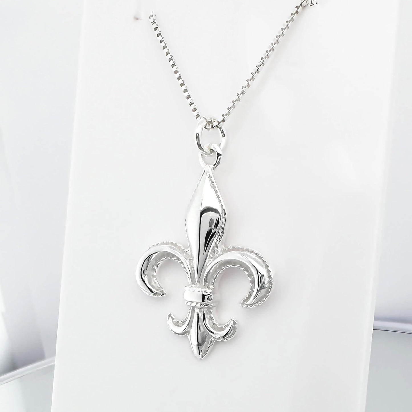 A silver-colored pendant necklace with a fleur-de-lis design.