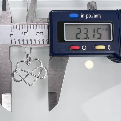 A silver heart-shaped pendant necklace is being measured with a ruler, and a digital caliper is also visible in the image.