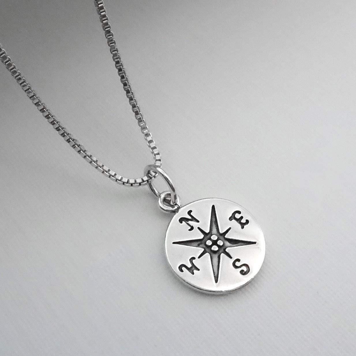 A silver-colored necklace with a compass pendant on it.