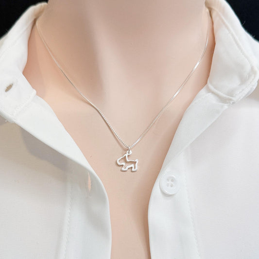 A silver necklace with a small pendant is worn around a person's neck, who is wearing a white collared shirt.