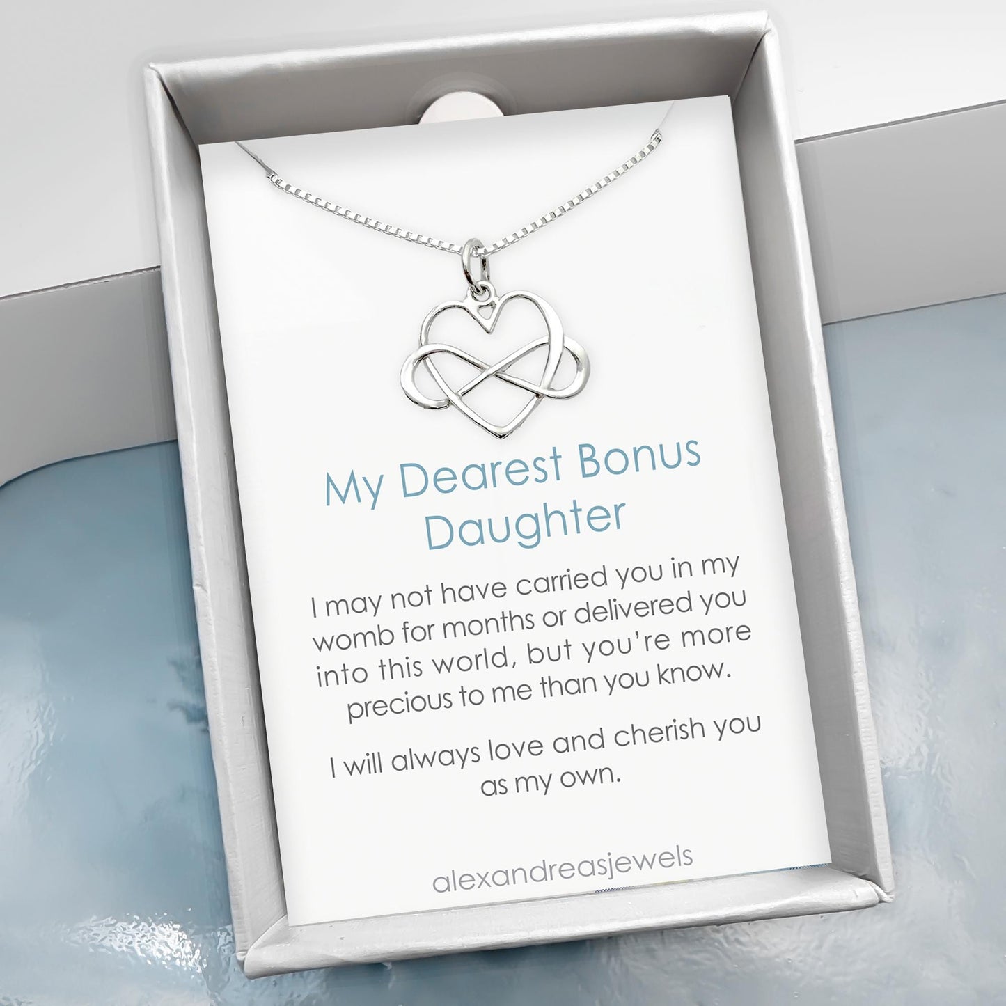 a silver necklace with a heart-shaped pendant, accompanied by a card that contains a heartfelt message about the mother-daughter relationship.