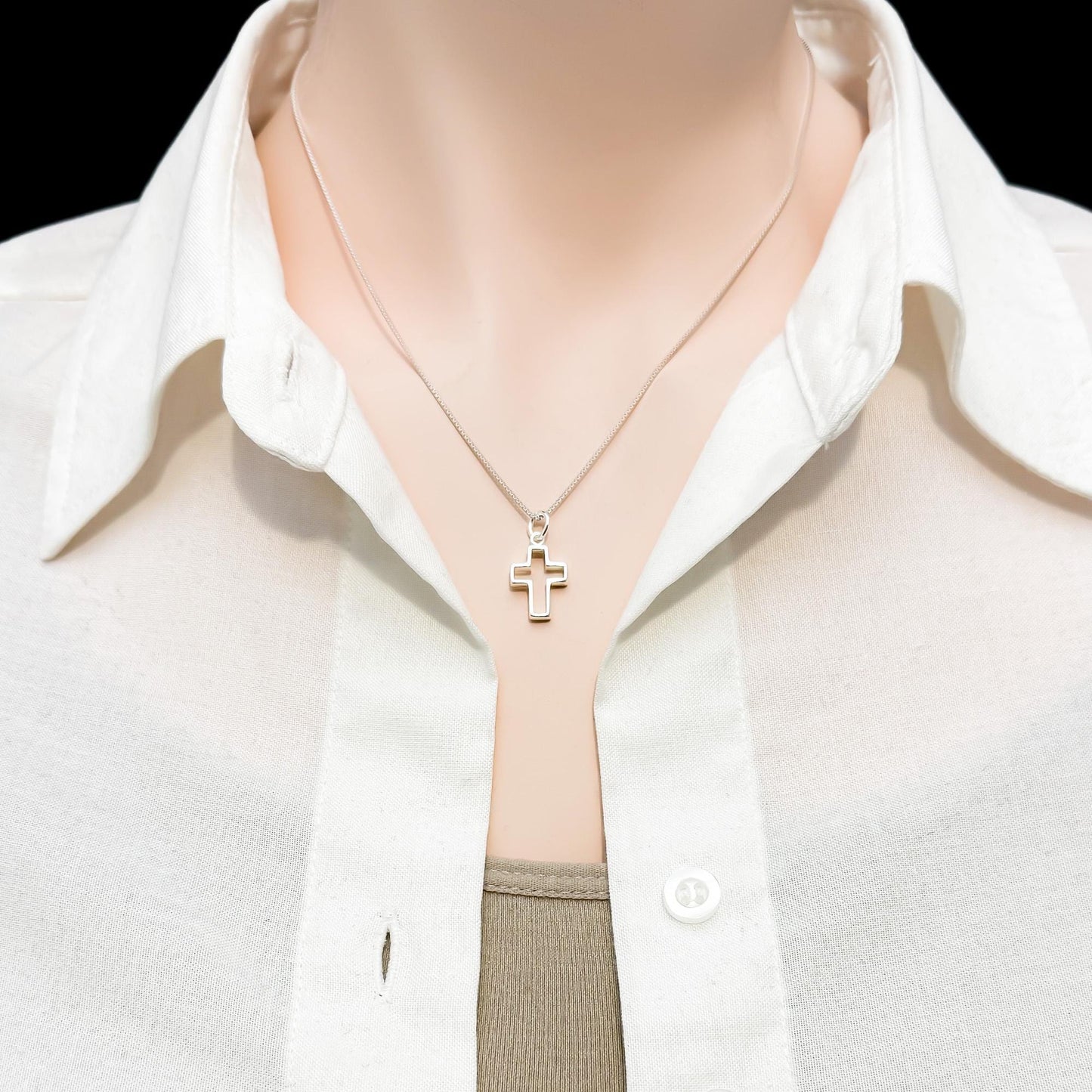 A close-up view of a person wearing a white collared shirt and a necklace with a cross pendant.
