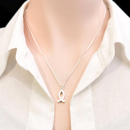 A silver necklace with a pendant is worn around a person's neck.