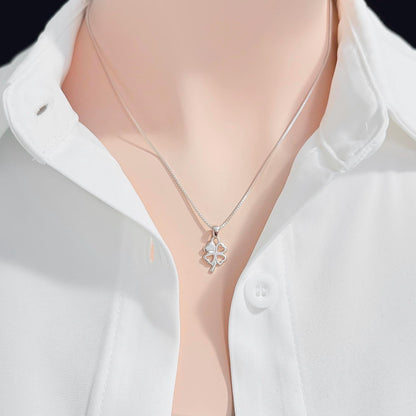 A silver necklace with a small pendant is worn around a person's neck, who is wearing a white collared shirt.