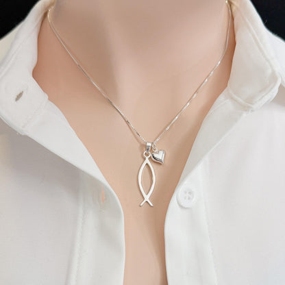 A silver necklace with a pendant featuring a fish design, worn around a person's neck.