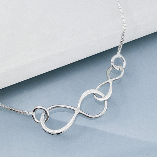 A silver necklace with a unique, abstract design consisting of interlocking circles or ovals.