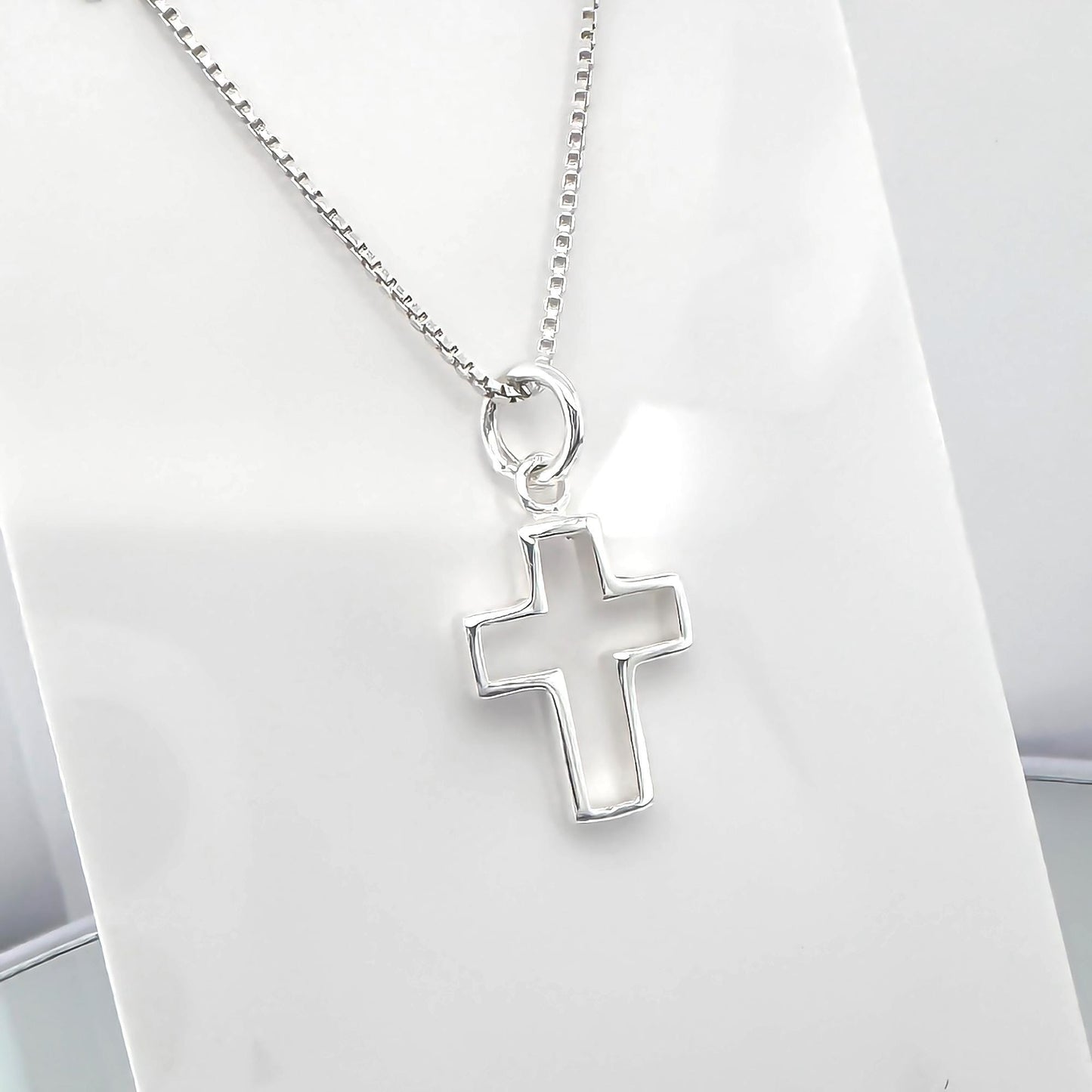 A silver cross pendant hanging from a chain.
