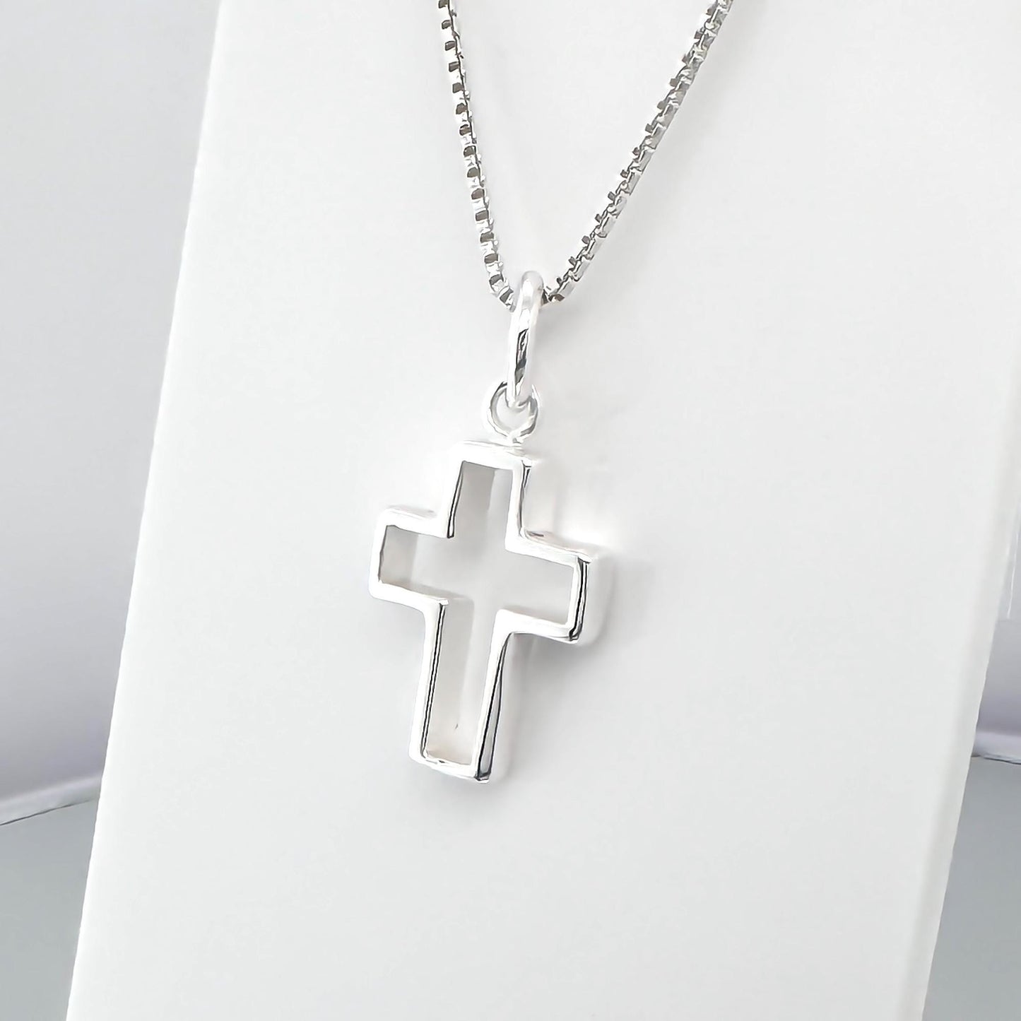 A silver cross pendant hanging from a chain.