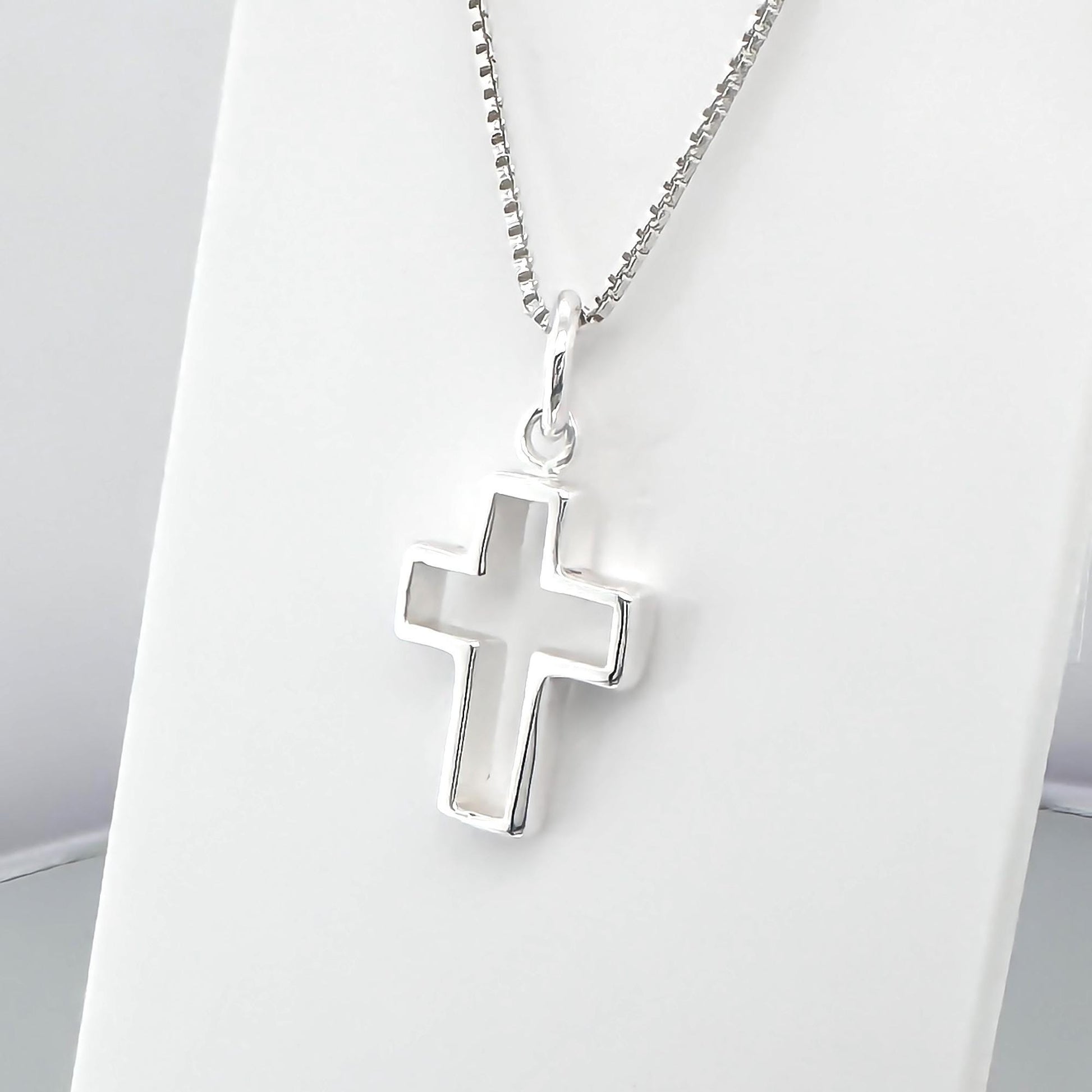 A silver cross pendant hanging from a chain.