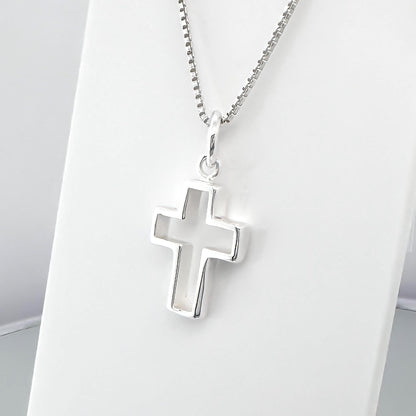 A silver cross pendant hanging from a chain.