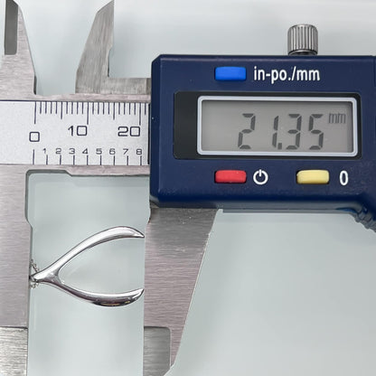 A digital caliper is being used to measure the size of a silver object, which appears to be a piece of jewelry.
