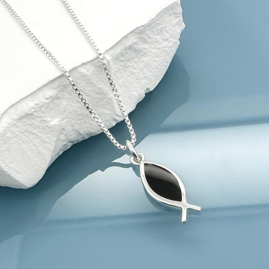 A silver necklace with a pendant featuring a black fish design is displayed against a blue background.