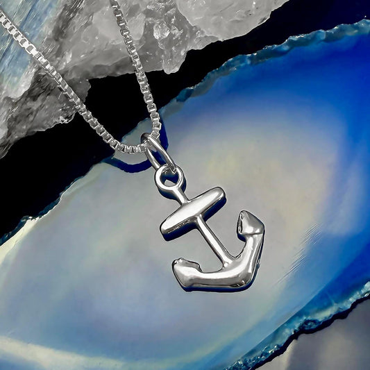 A silver anchor pendant is displayed on a chain against a blue background.