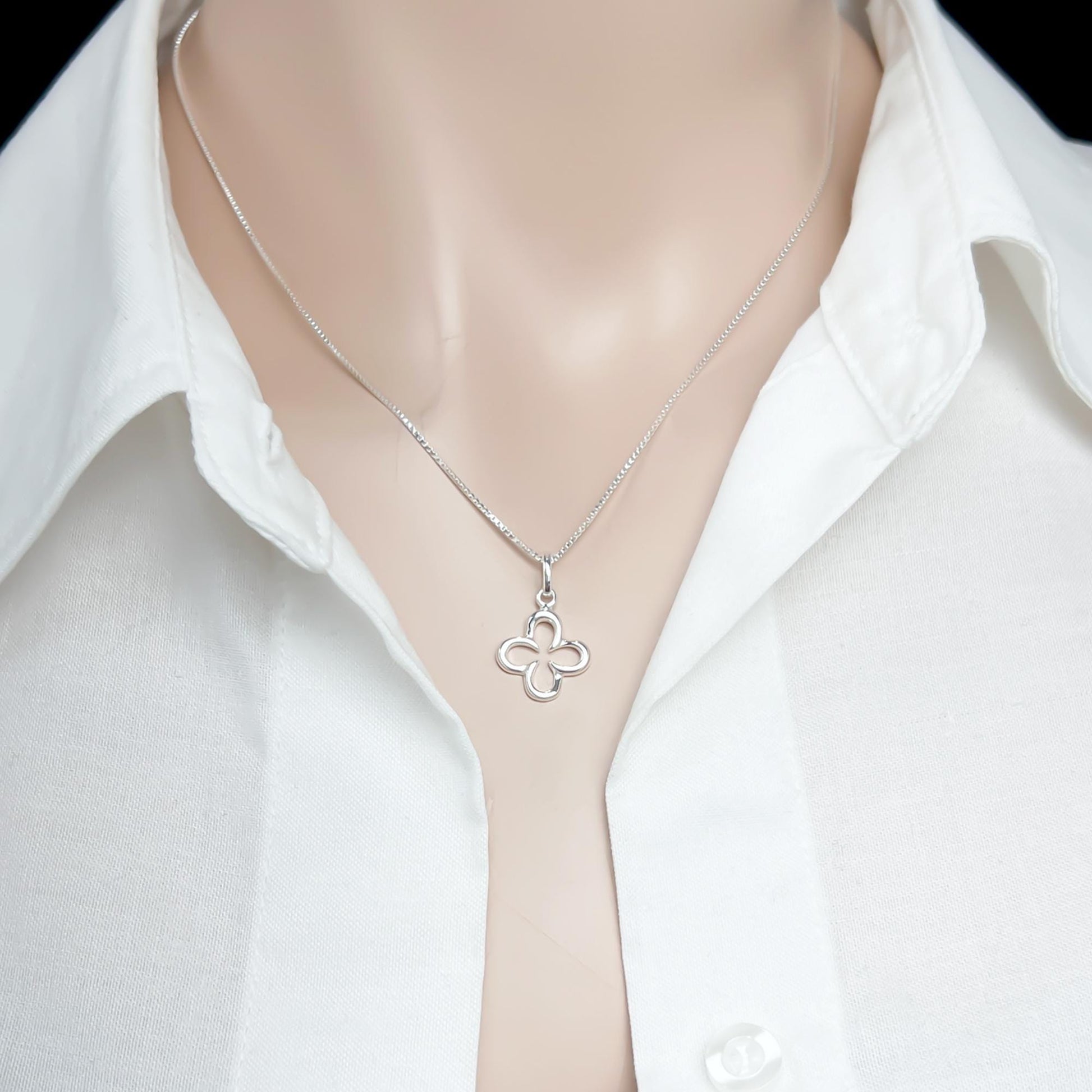 A silver necklace with a pendant is worn around a mannequin's neck, and the mannequin is wearing a white collared shirt.