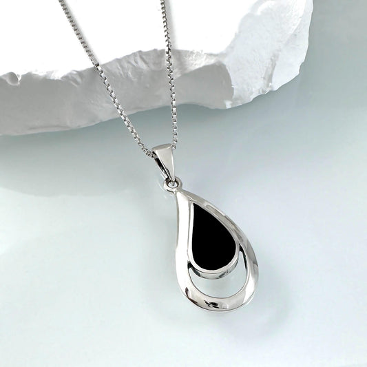 A silver necklace with a pendant featuring a black oval-shaped design.
