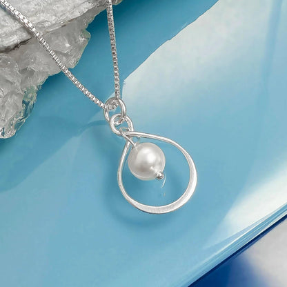 A silver necklace with a pearl pendant is displayed against a blue background.