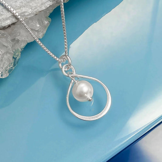 A silver necklace with a pearl pendant is displayed against a blue background.