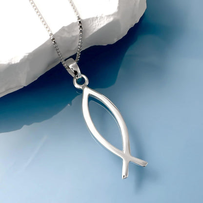A silver fish pendant necklace is displayed against a blue background.