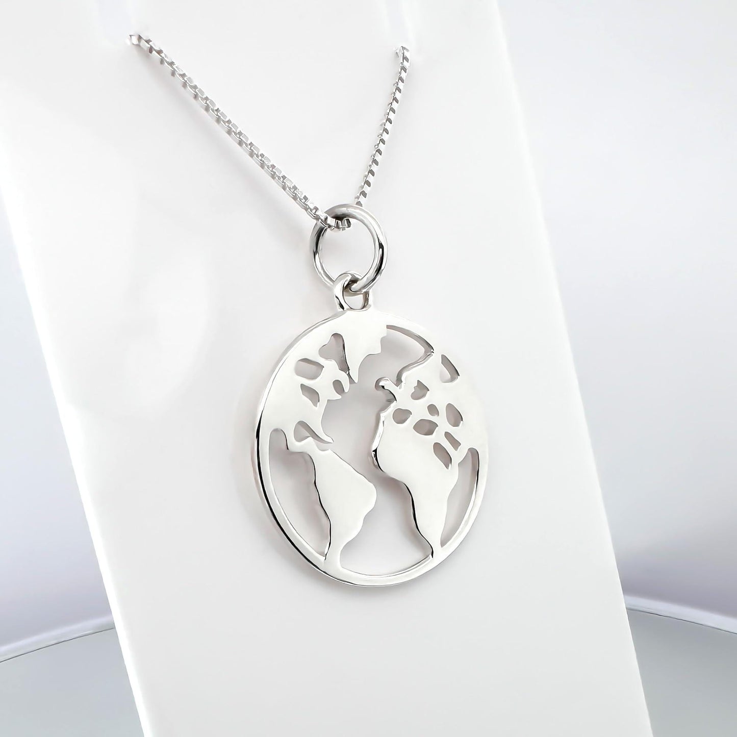 A silver necklace with a circular pendant featuring a world map design.