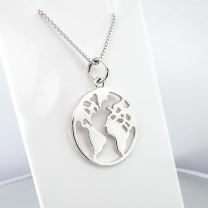 A silver necklace with a circular pendant featuring a world map design.