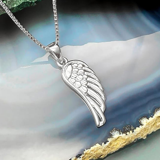 A silver-colored pendant in the shape of a wing is displayed against a blue and white background.