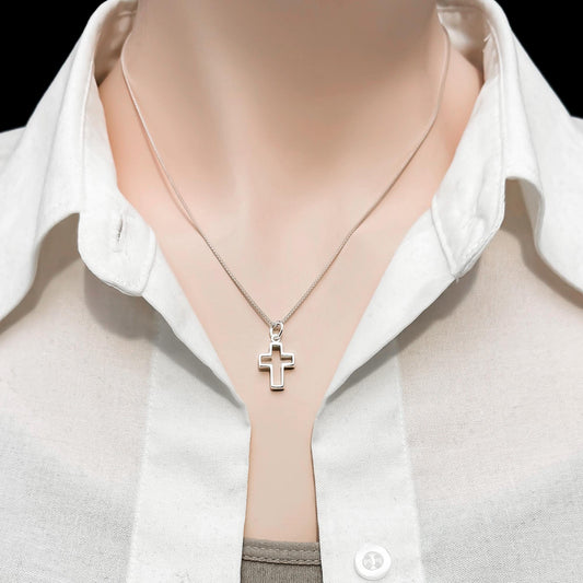 A close-up of a person wearing a white collared shirt and a silver cross necklace.