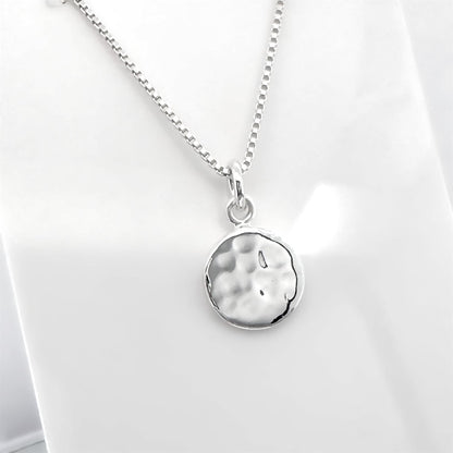 A silver necklace with a round pendant is shown against a white background.
