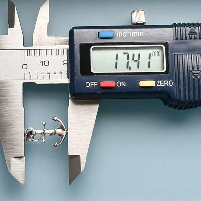 A digital caliper is being used to measure the size of a small object, which appears to be an anchor. The caliper is displaying the size of the object as 17.41 millimeters.
