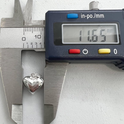 A silver heart-shaped charm is being measured with a caliper, which displays the size as 1.65 millimeters.