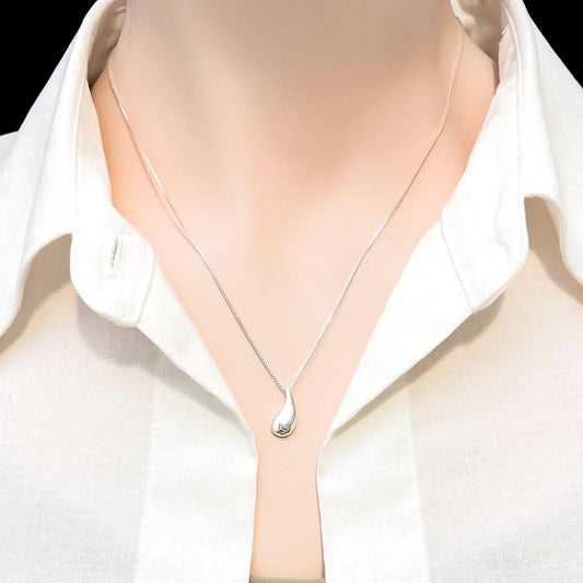 A close-up view of a mannequin wearing a white collared shirt and a silver necklace with a pendant.