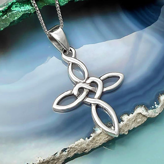 A silver cross pendant with intricate knotwork design, suspended from a chain against a blue and green background.