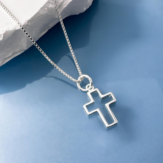 A silver cross pendant necklace is displayed against a blue background.