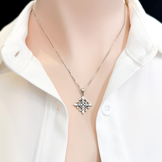 A silver necklace with a pendant is displayed on a person wearing a white collared shirt.