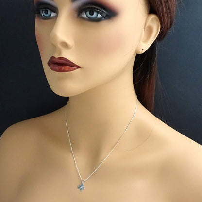 A mannequin head wearing a silver necklace with a pendant.
