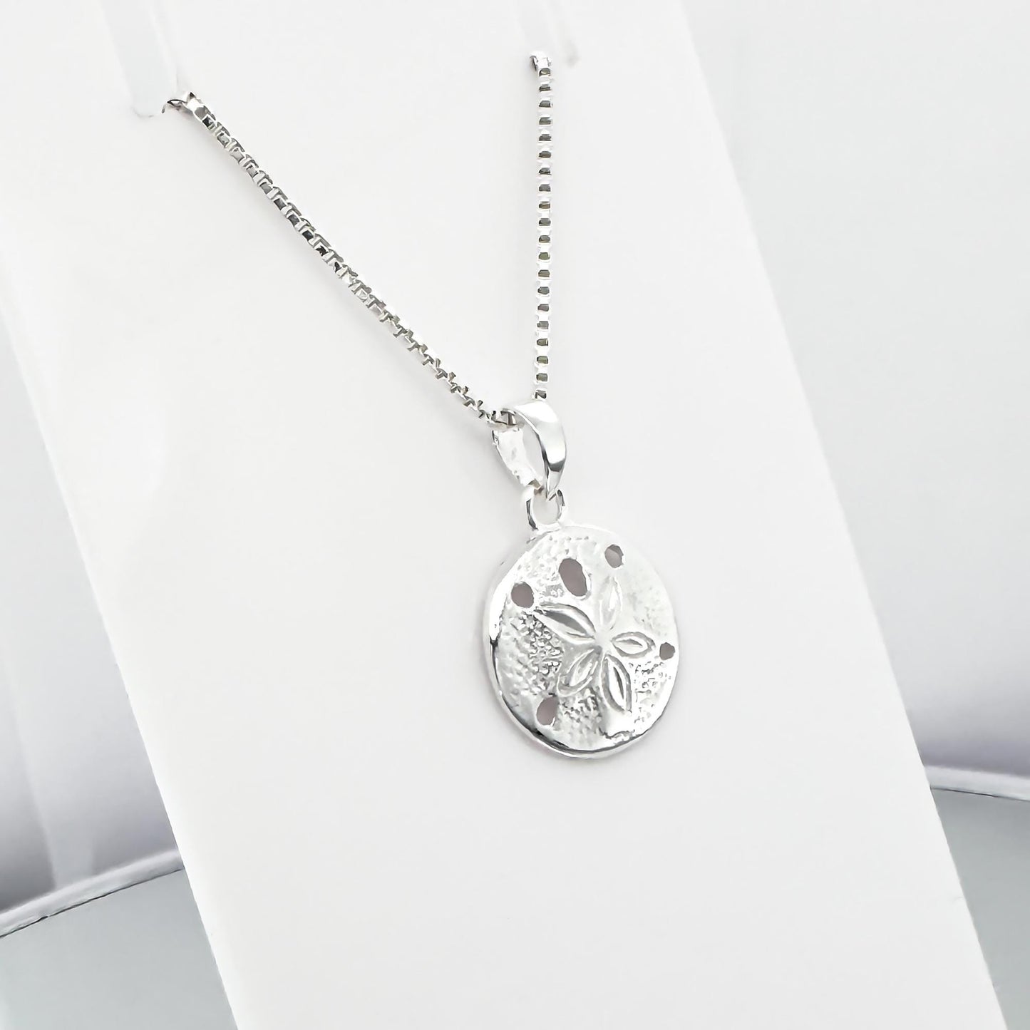 A silver necklace with a round pendant featuring a floral design.