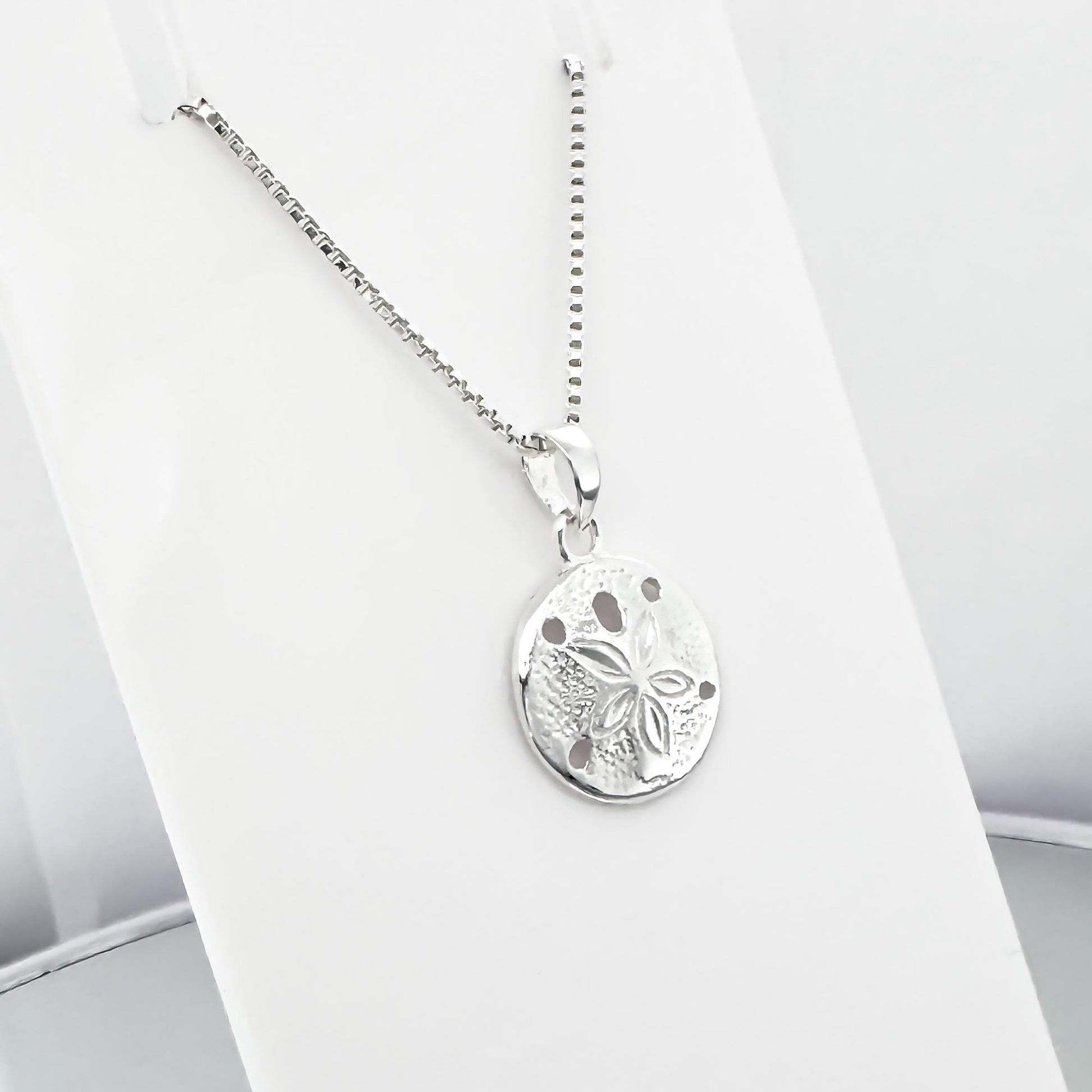 A silver necklace with a round pendant featuring a floral design.
