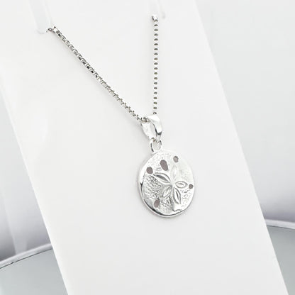 A silver necklace with a round pendant featuring a floral design.