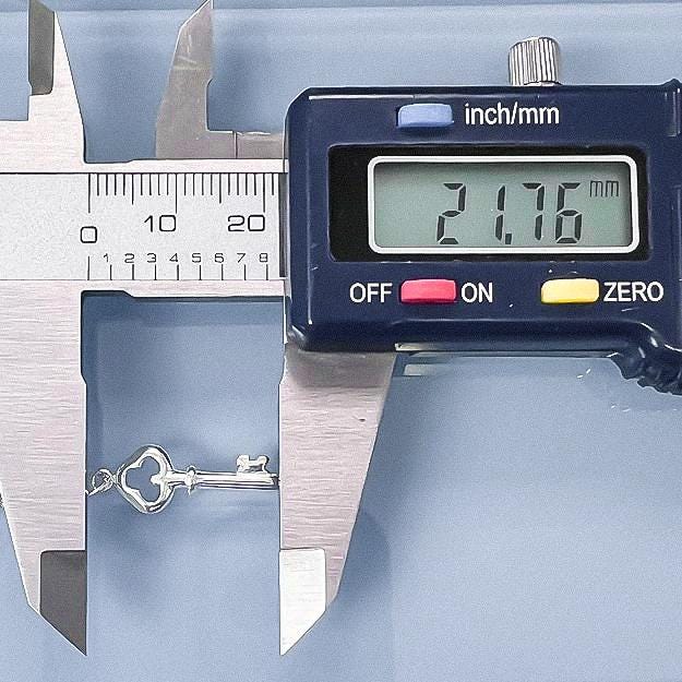 A digital caliper is being used to measure the size of a key chain, displaying the size as 2.7 inches.