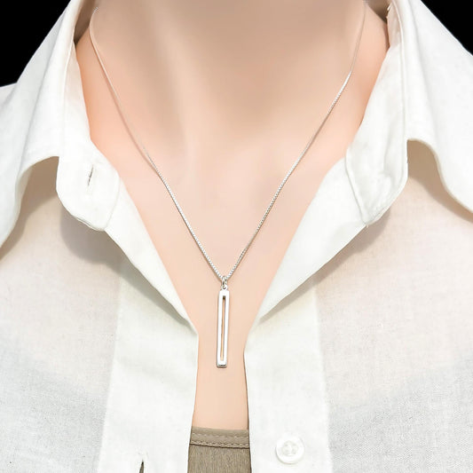 A silver necklace with a rectangular pendant is displayed on a mannequin's neck.