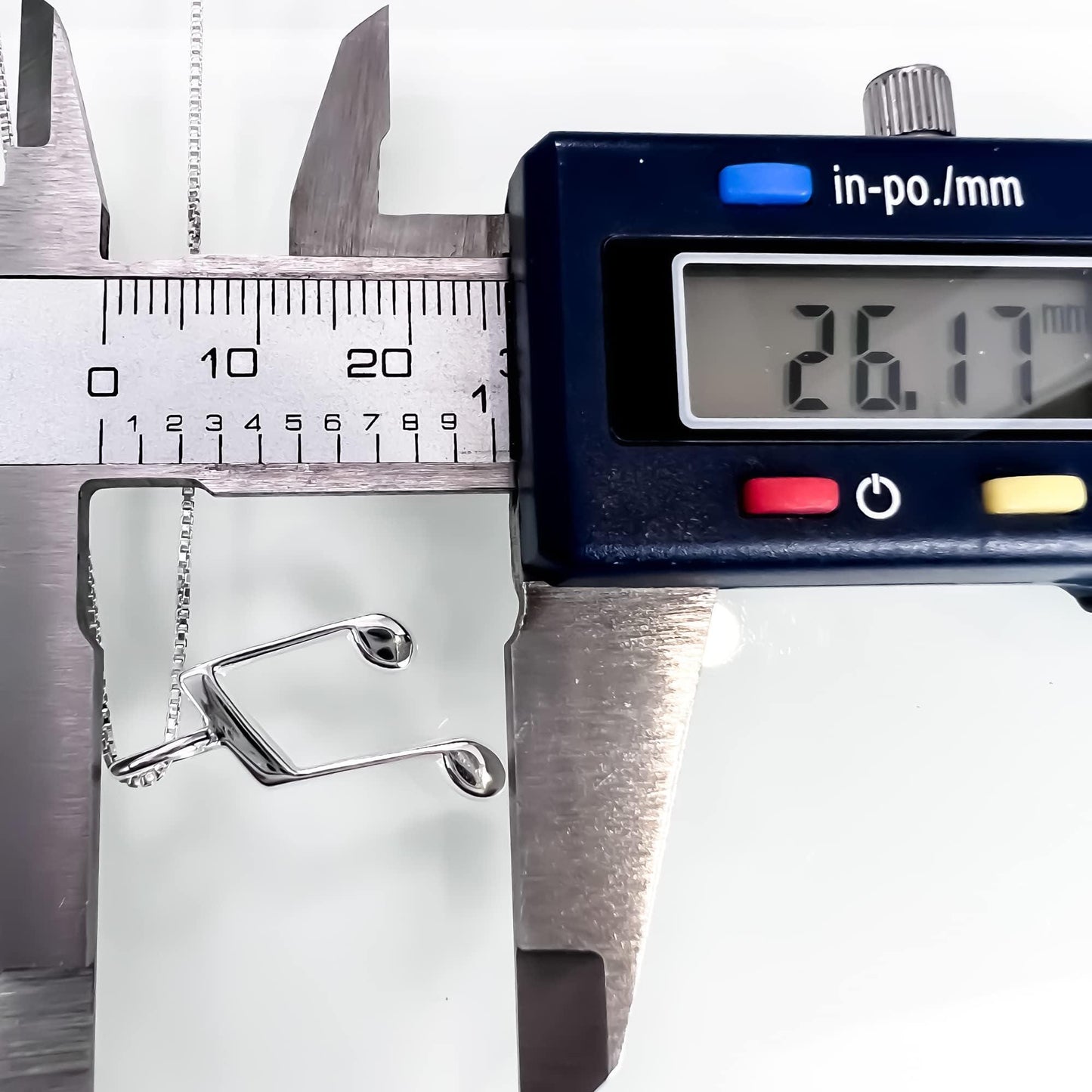 A digital caliper is being used to measure the size of a silver chain.